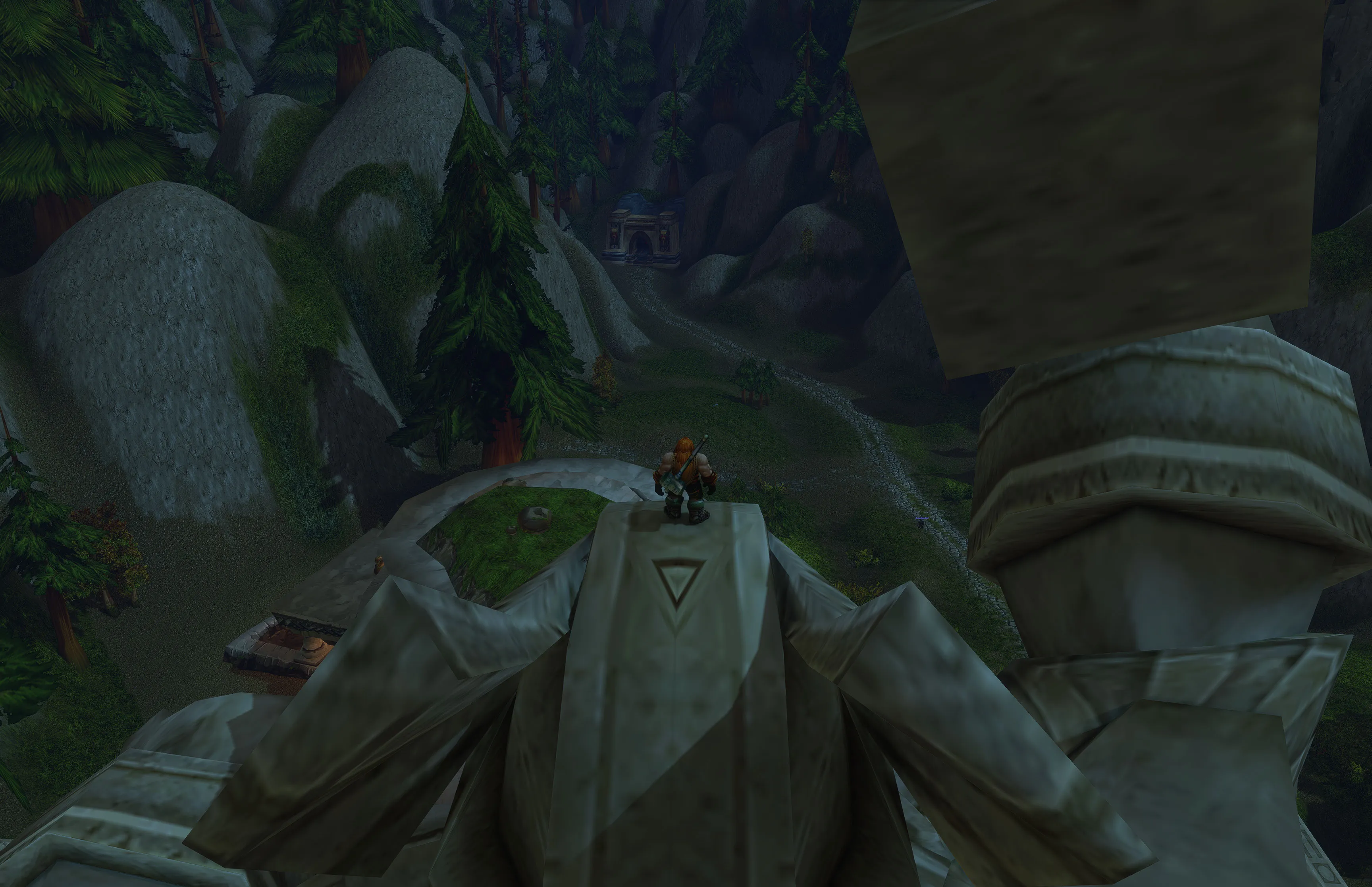 Nuir standing high on a statue, looking down at the road and mountain tunnel.